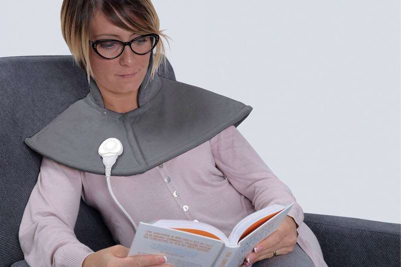 Persona leyendo con la almohadilla eléctrica Alpak LTK730 colocada sobre cuello y hombros