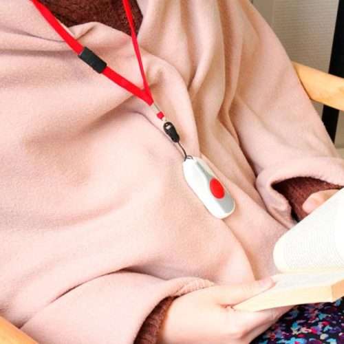 Mujer mayor usando colgante con pulsador de emergencia en casa
