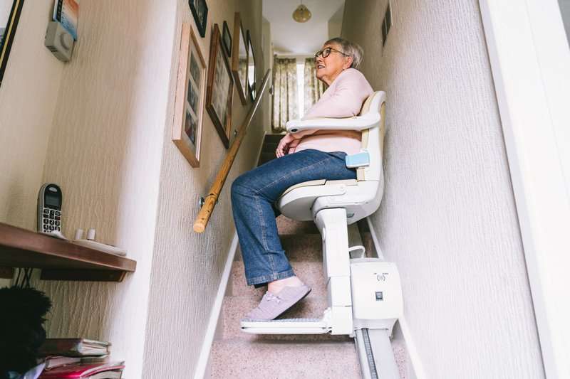 Mujer subiendo escaleras en silla salvaescaleras con instalación