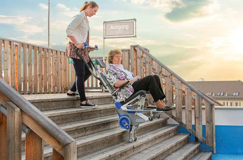 Mujer bajando escaleras en silla salvaescaleras portátil