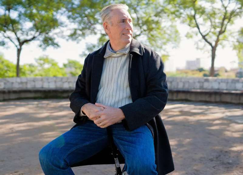 Hombre mayor usando bastón con asiento en parque