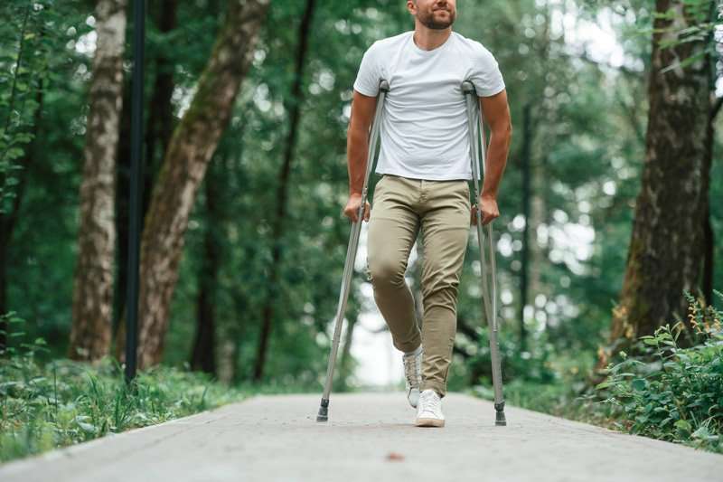 Persona caminando con muletas en fase de recuperación tras una fractura de pie