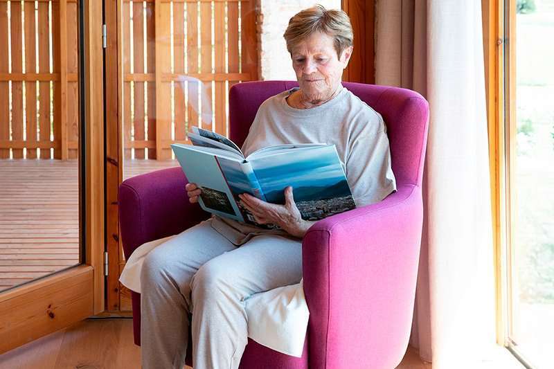 Mujer mayor leyendo en un sillón con protector discreto