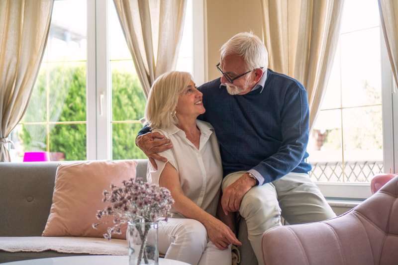 Pareja de personas mayores sentados en el salón disfrutando de su sillón