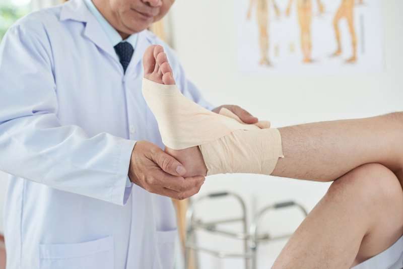 Médico examinando el pie vendado de un paciente en fase de recuperación tras una fractura
