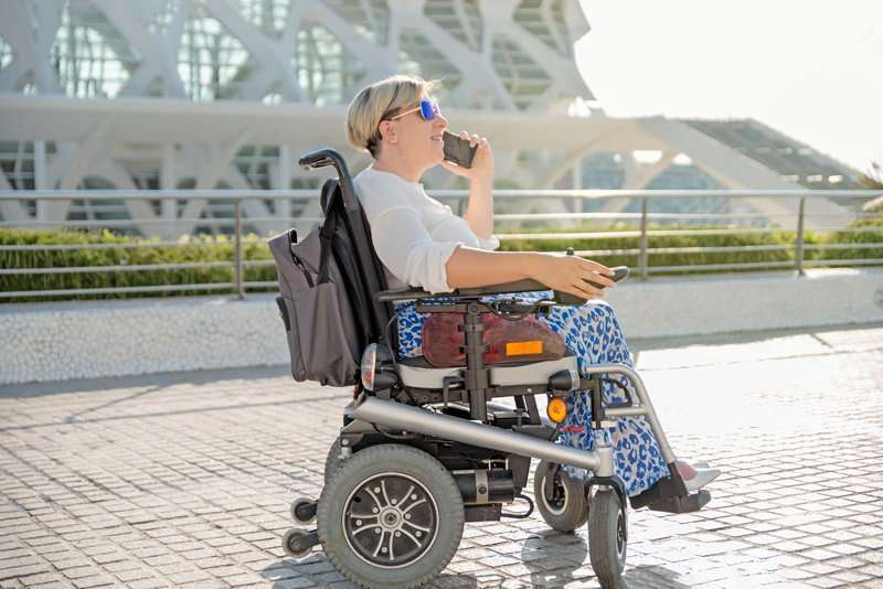Mujer usando silla de ruedas eléctrica compacta en exteriores