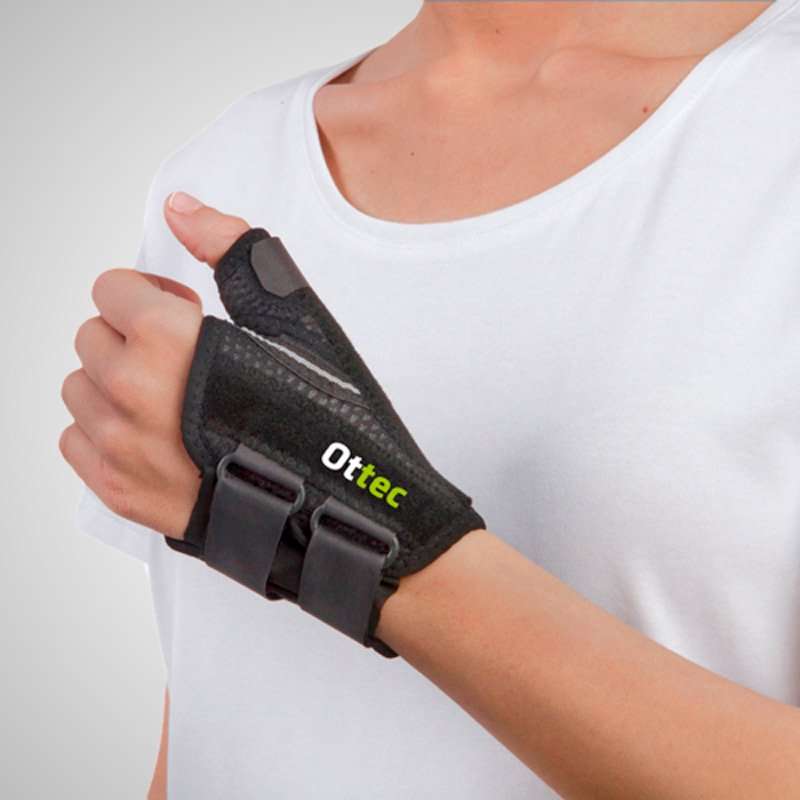 Persona con ortesis estabilizadora de pulgar negra Ottec con cierre de velcro en la muñeca