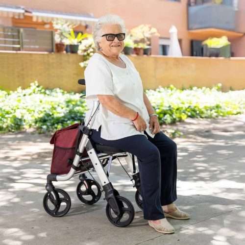 Persona sentada en el andador rollator Lett Walk en exterior