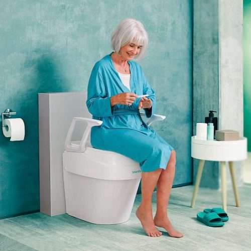 Persona sentada en elevador de WC Smartfix con reposabrazos abatibles