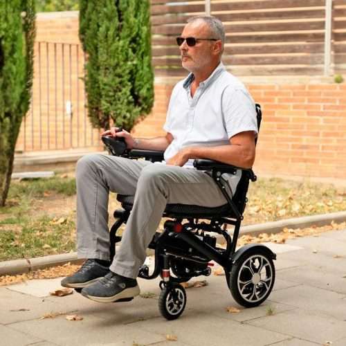 Persona usando la silla eléctrica R650 en exterior con mando de control en reposabrazos