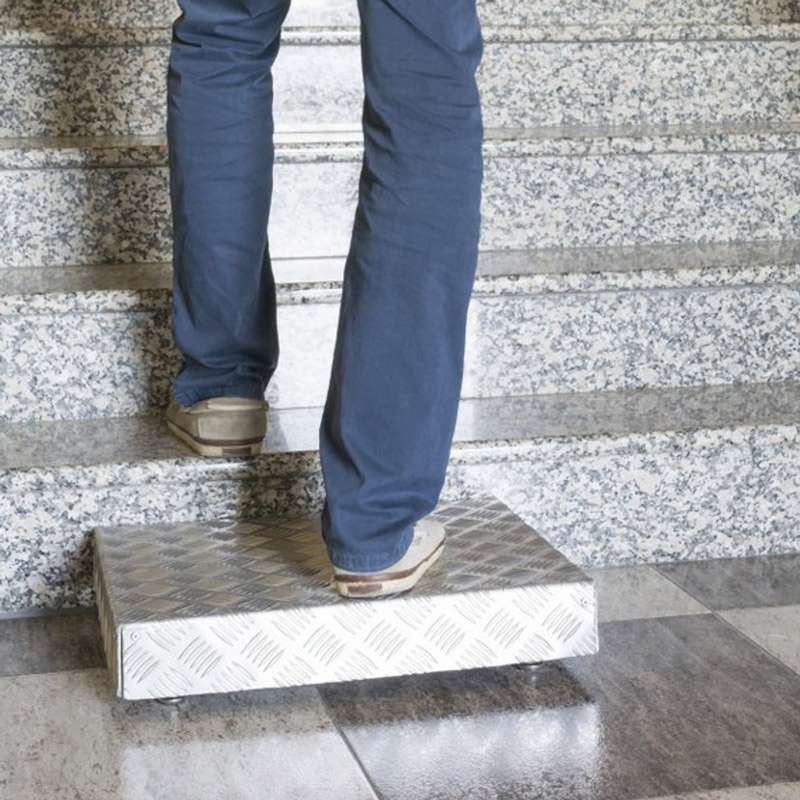 Escalón regulable de acero inoxidable colocado frente a unas escaleras