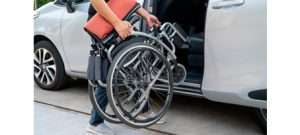 Silla de ruedas plegable junto a un coche