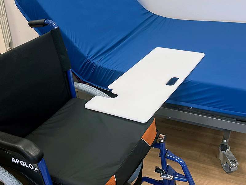 Tabla de transferencia con acople para silla de ruedas colocada para facilitar el traslado a la cama