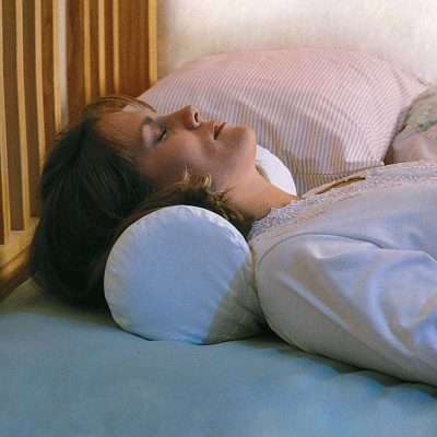 Persona tumbada usando el rollo cervical Rolling Cushion como apoyo bajo el cuello
