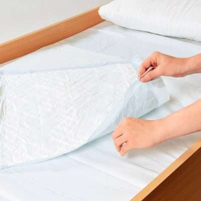 Empapador desechable Abri-Soft Classic colocado sobre una cama para proteger el colchón