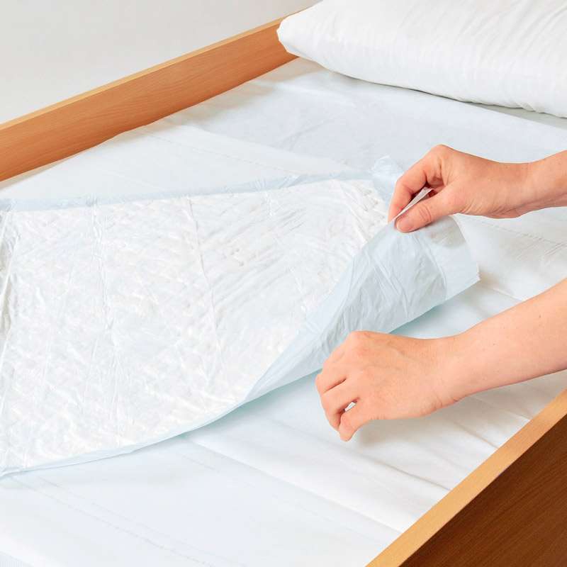Empapador desechable Abri-Soft Classic colocado sobre una cama para proteger el colchón