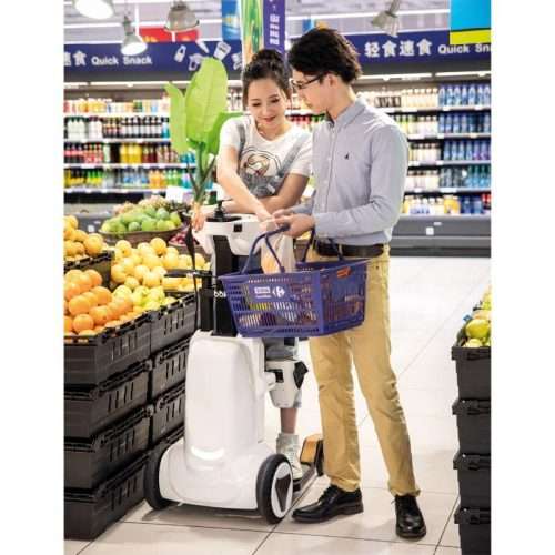 Pareja realizando la compra en un supermercado con la ayuda de la silla bipedestadora interactuando a la altura de los ojos