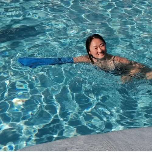Mujer nadando en piscina con protector impermeable de escayola en el brazo