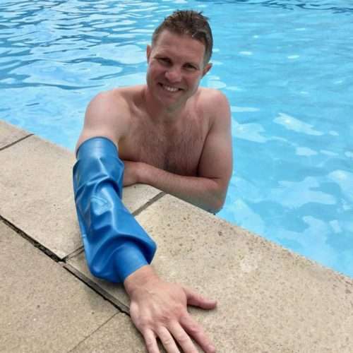 Hombre nadando en piscina con protector impermeable en el codo